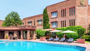 Een hotel met een zwembad, terras en een gevel van baksteen.