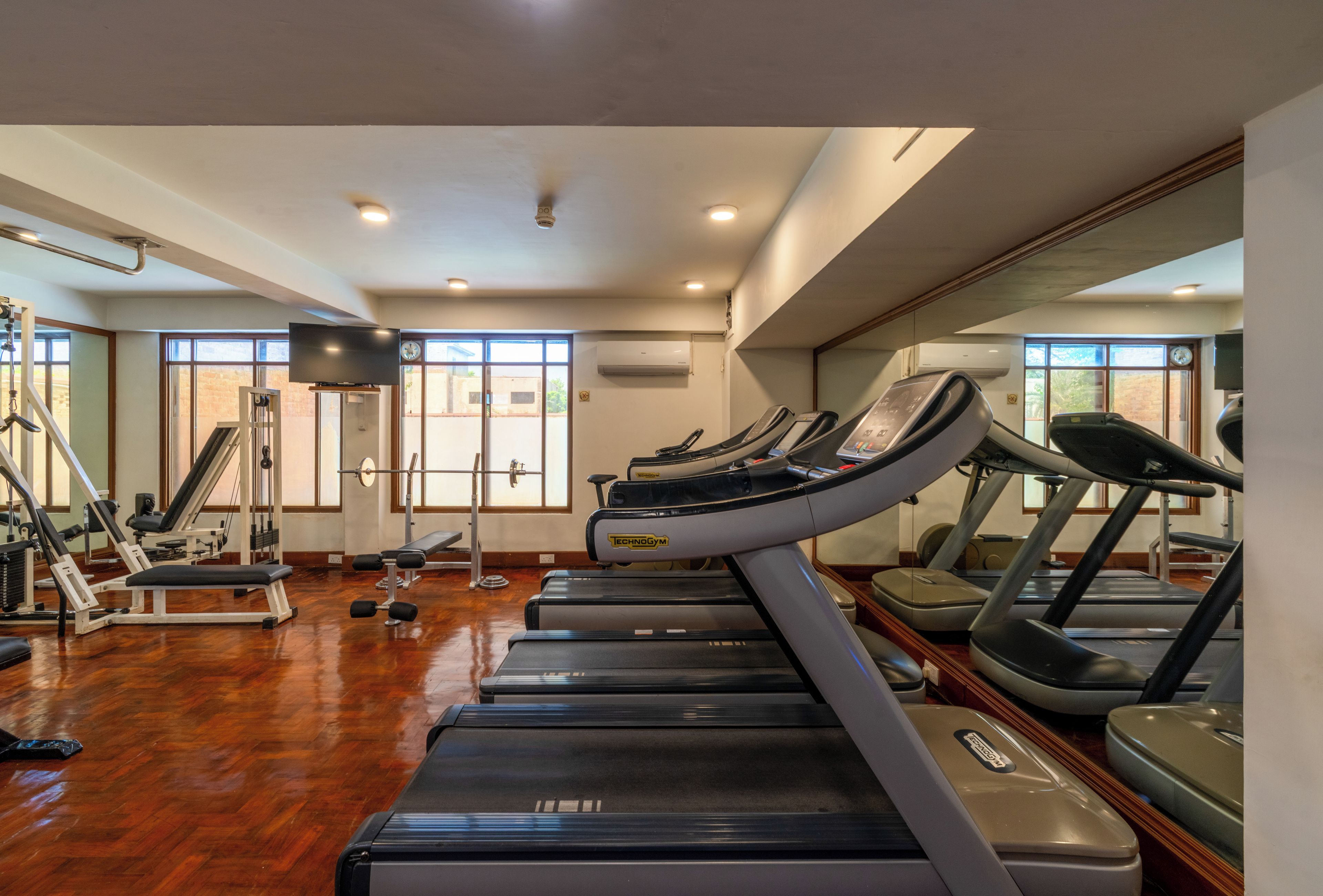 A gym with treadmills, weight machines, and a large mirror.
