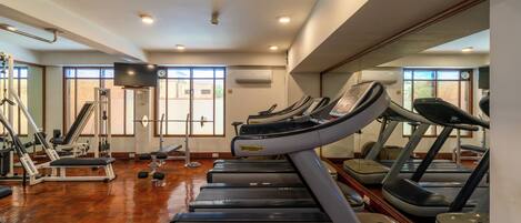 A gym with treadmills, weight machines, and a large mirror.