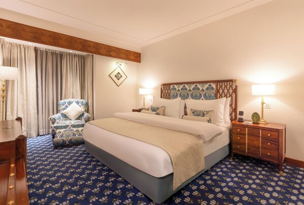 A hotel room with a large bed, a chair, a nightstand, and a lamp.