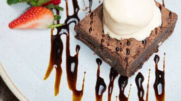 A dessert plate with a brownie, ice cream, and chocolate drizzle.