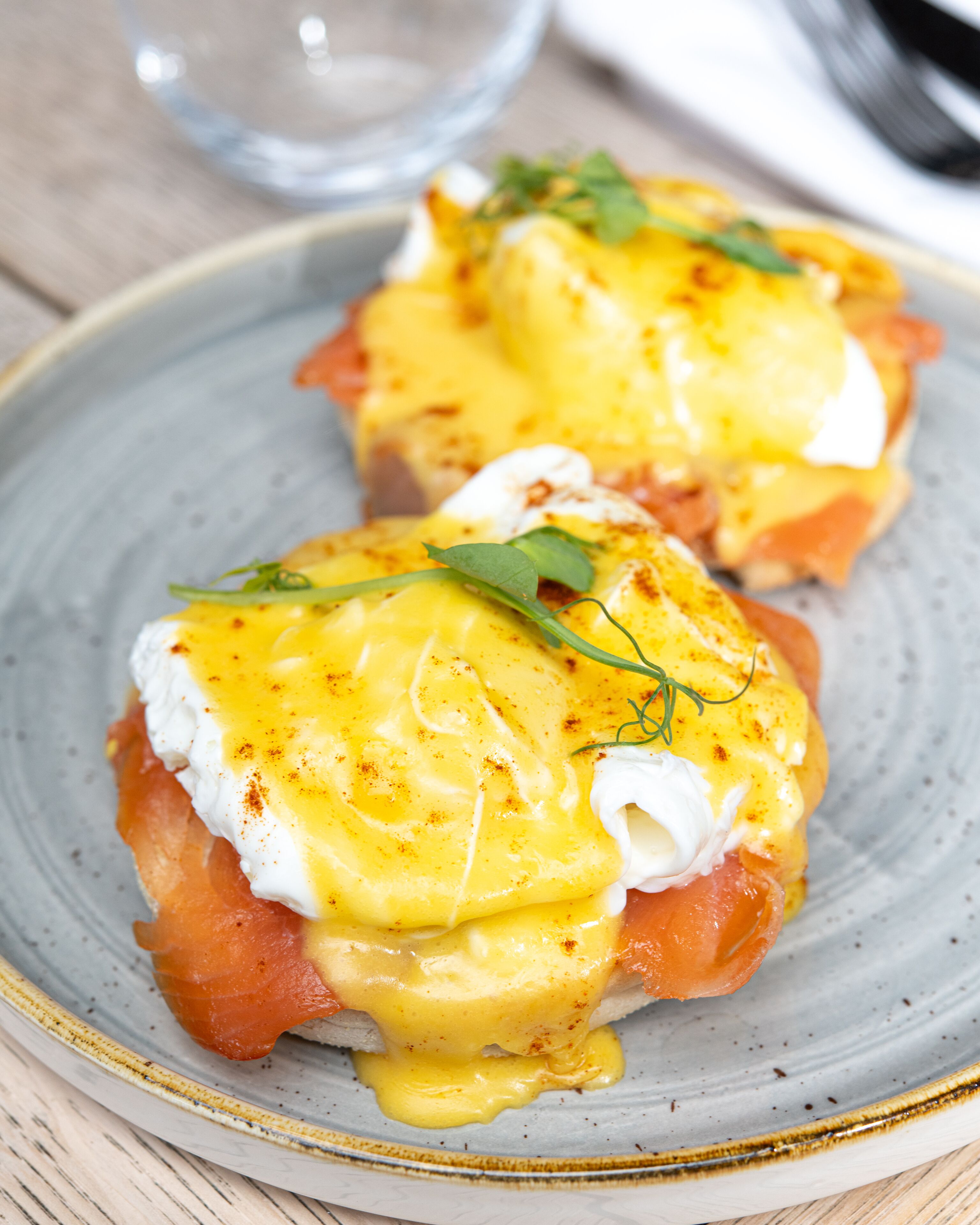 A plate of eggs benedict with hollandaise sauce, garnished with herbs.
