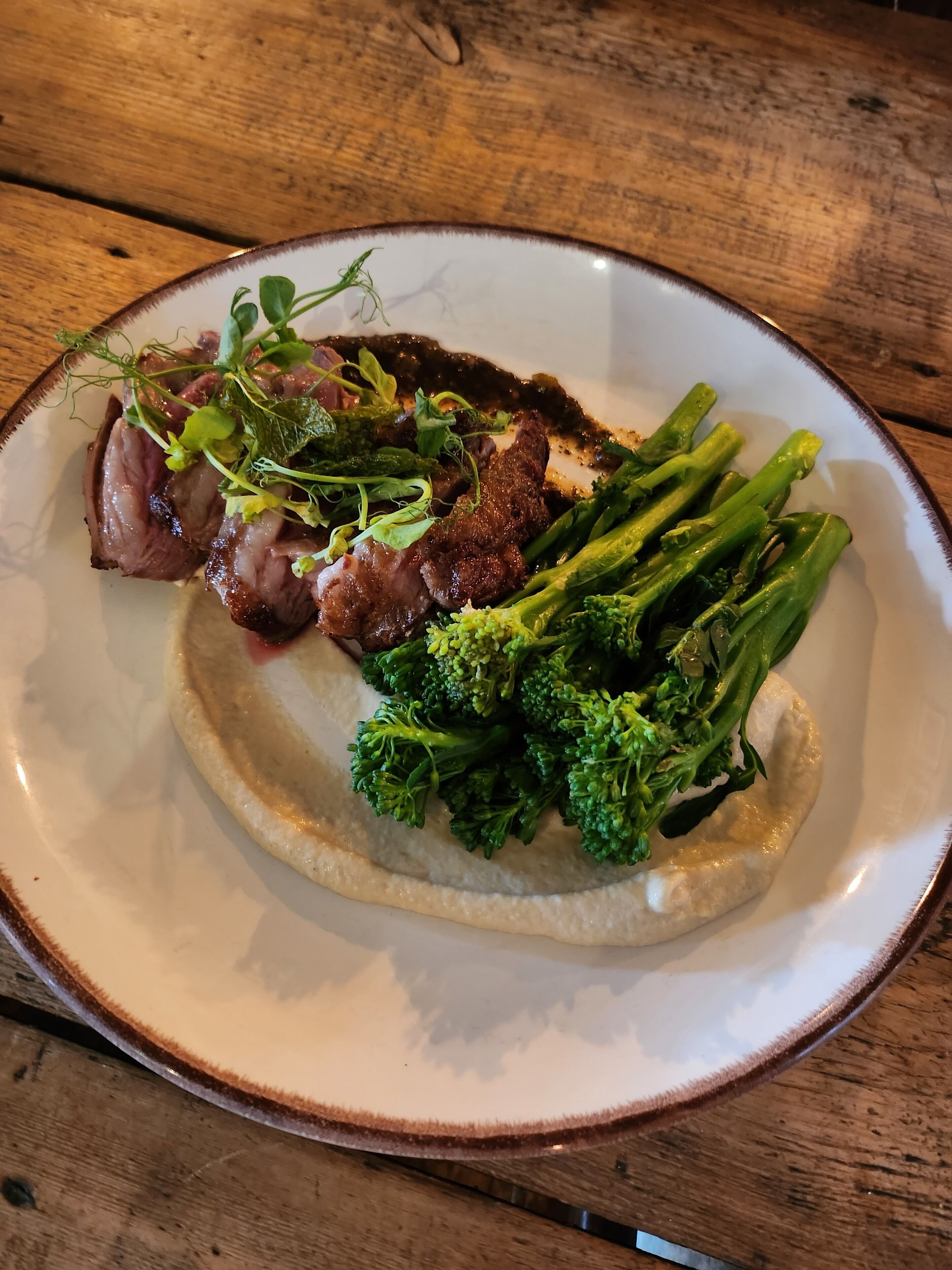 Une assiette de nourriture comprenant de la viande, des brocolis et des légumes verts, le tout présenté sur une assiette blanche.