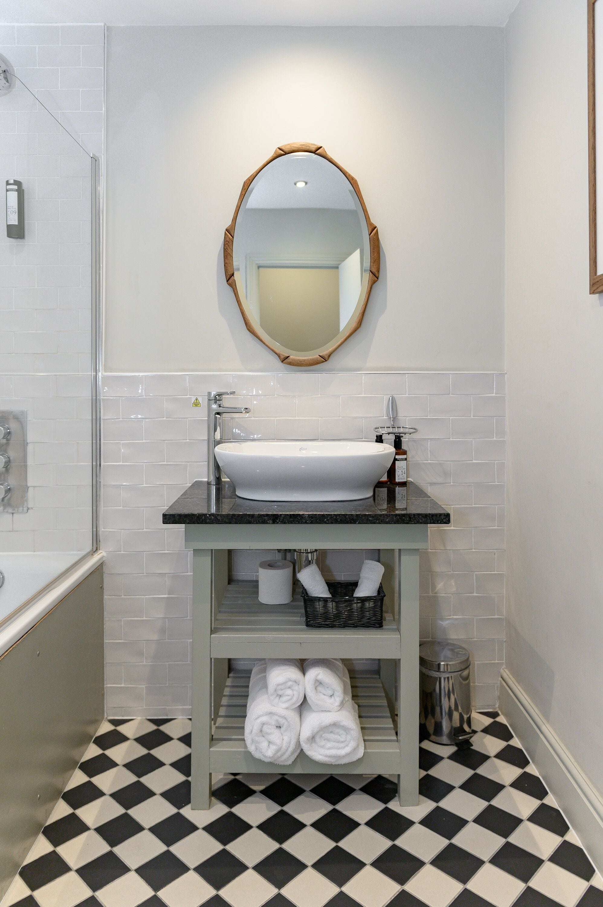 A bathroom with a white sink, a mirror, and a black and white checkered floor.