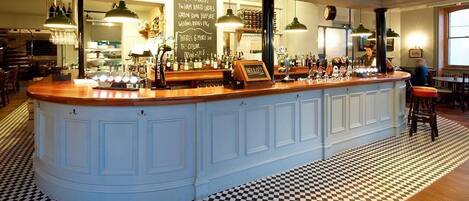 A bar area with a checkered floor, a wooden counter, and a chalkboard menu.
