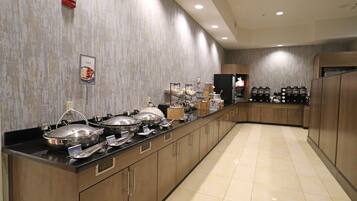A buffet setup with multiple serving stations, a coffee machine, and a fire alarm on the wall.