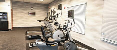 A gym with stationary bikes, treadmills, and a wall clock.