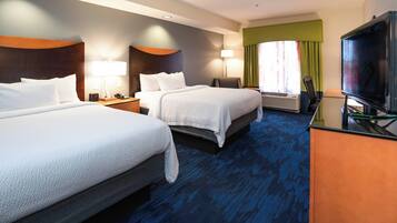 A hotel room with two beds, a desk with a television, and a window with curtains.