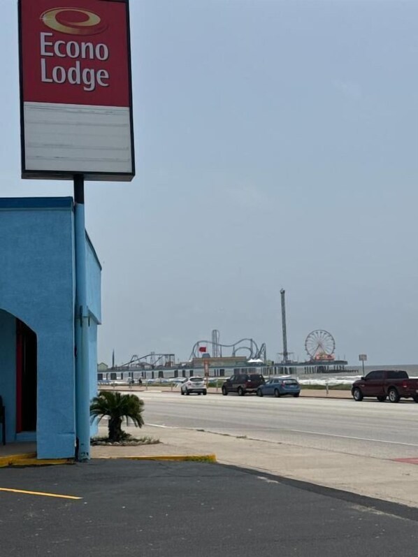 Un letrero de Econo Lodge, un edificio con fachada azul, y un estacionamiento con varios coches.