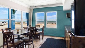 Un comedor con vista a la playa, un televisor y un ventanal grande.