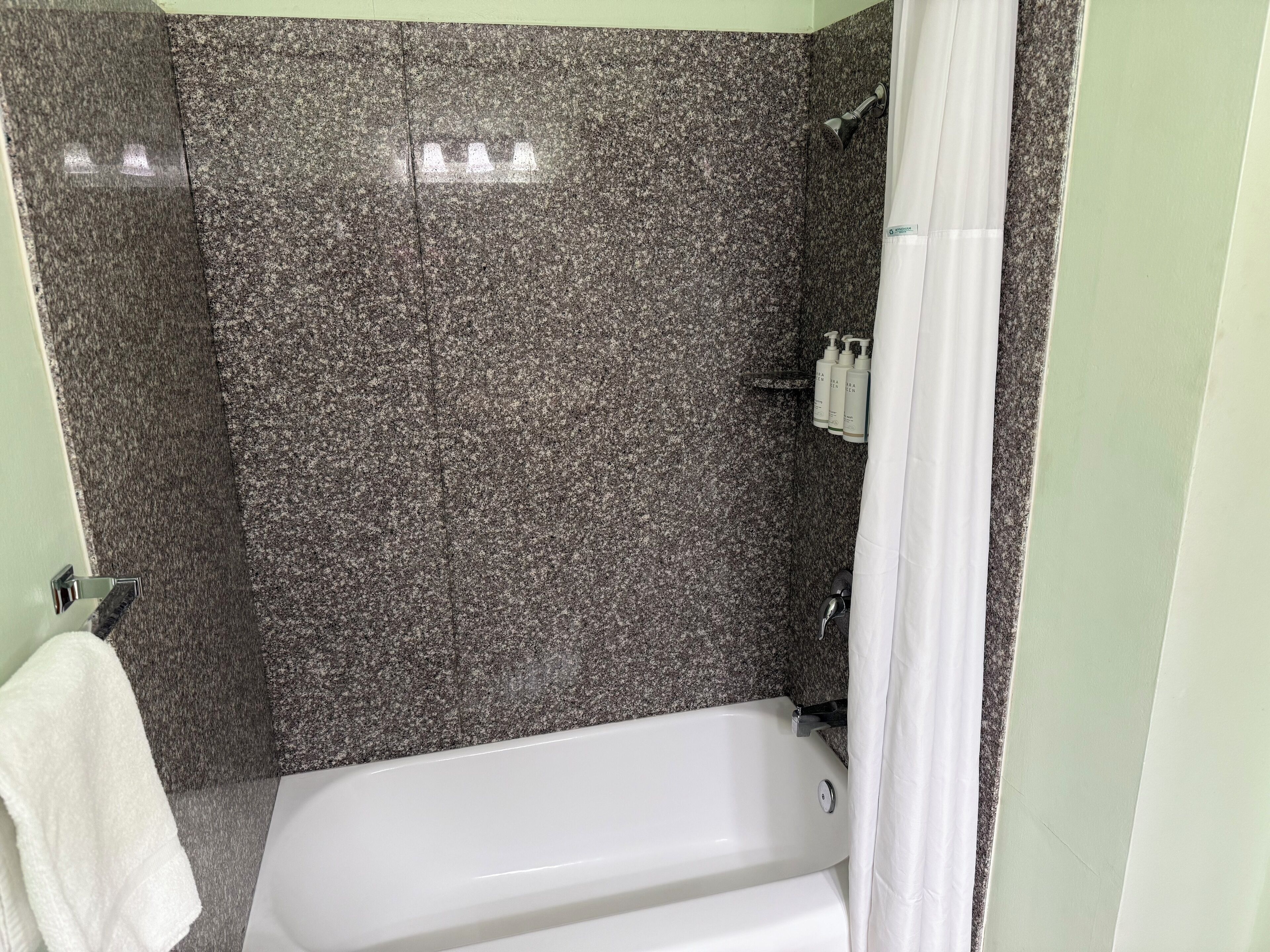 Un baño con una bañera blanca, zona de ducha y un perchero para toallas.