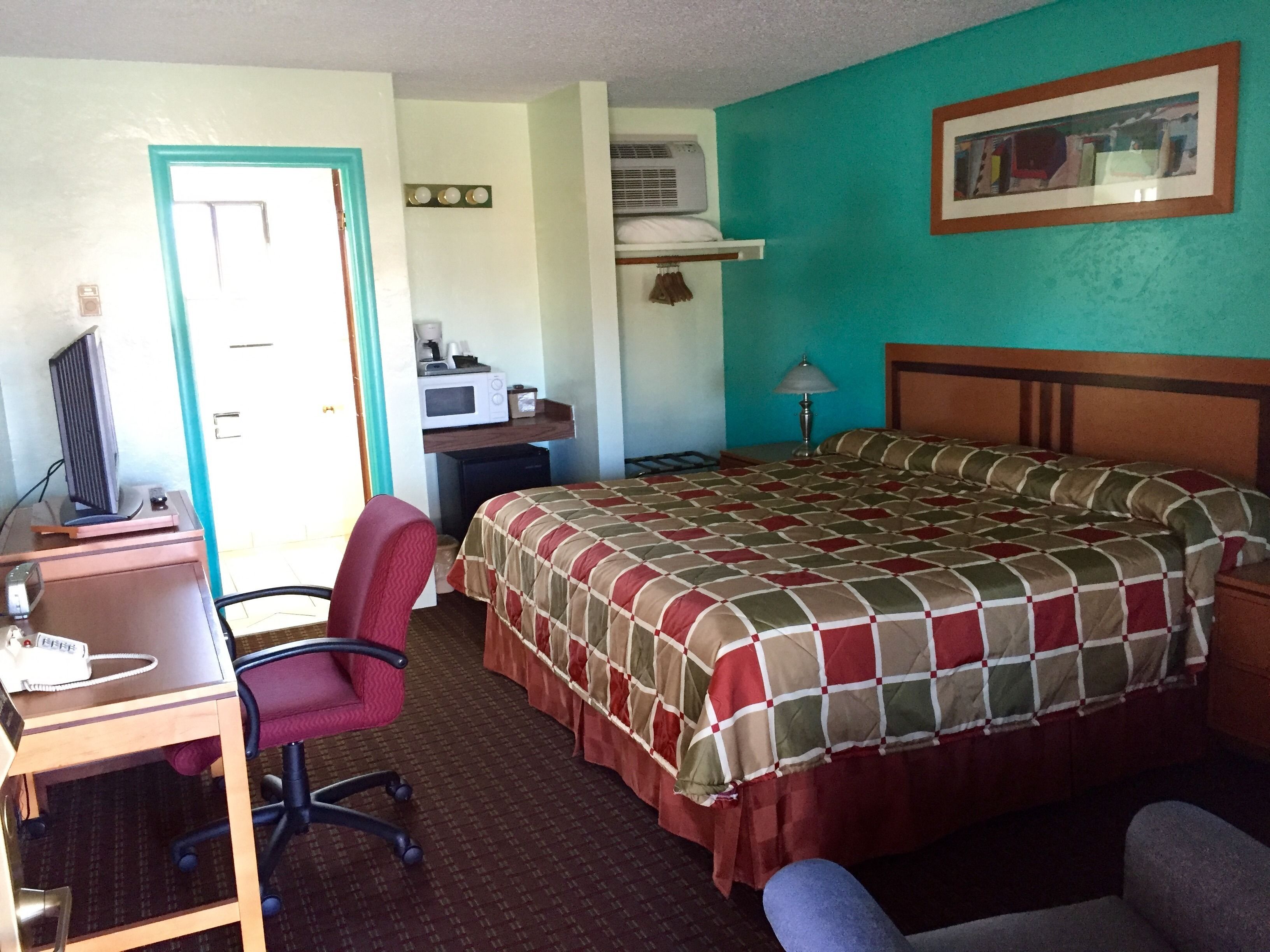 Habitación de hotel con cama, escritorio, silla y televisor.
