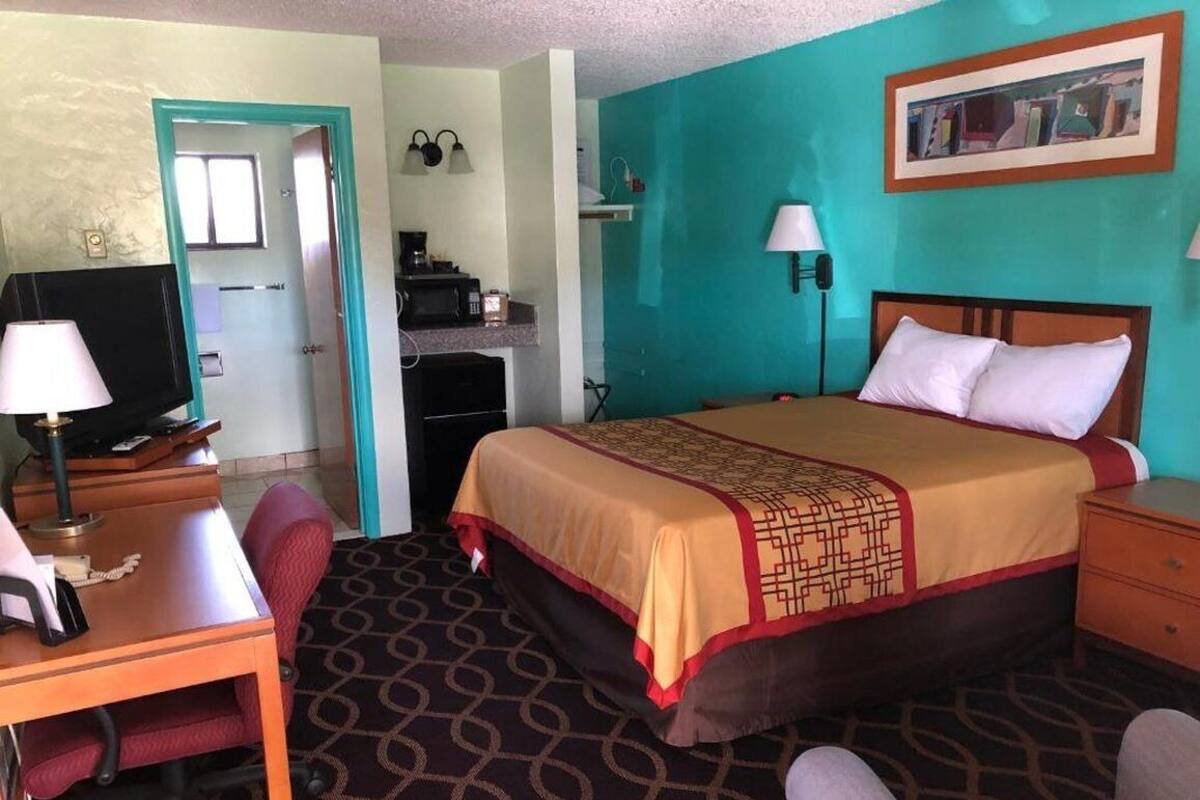 A hotel room with a bed, desk, chair, and a television.