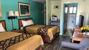Habitaci ón de hotel con dos camas, un escritorio, una silla, un microondas y un televisor.