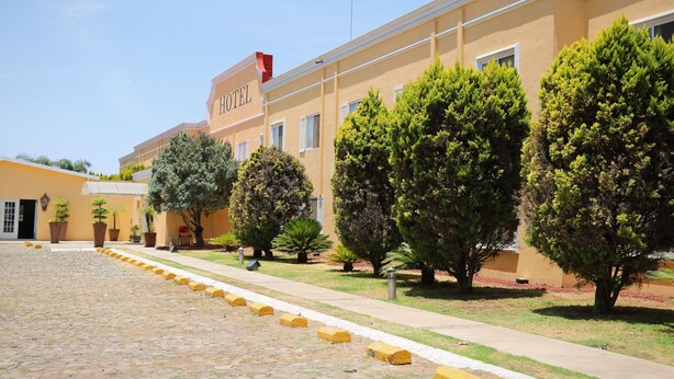 Un hotel con un patio empedrado, plantas en macetas y cielo despejado.