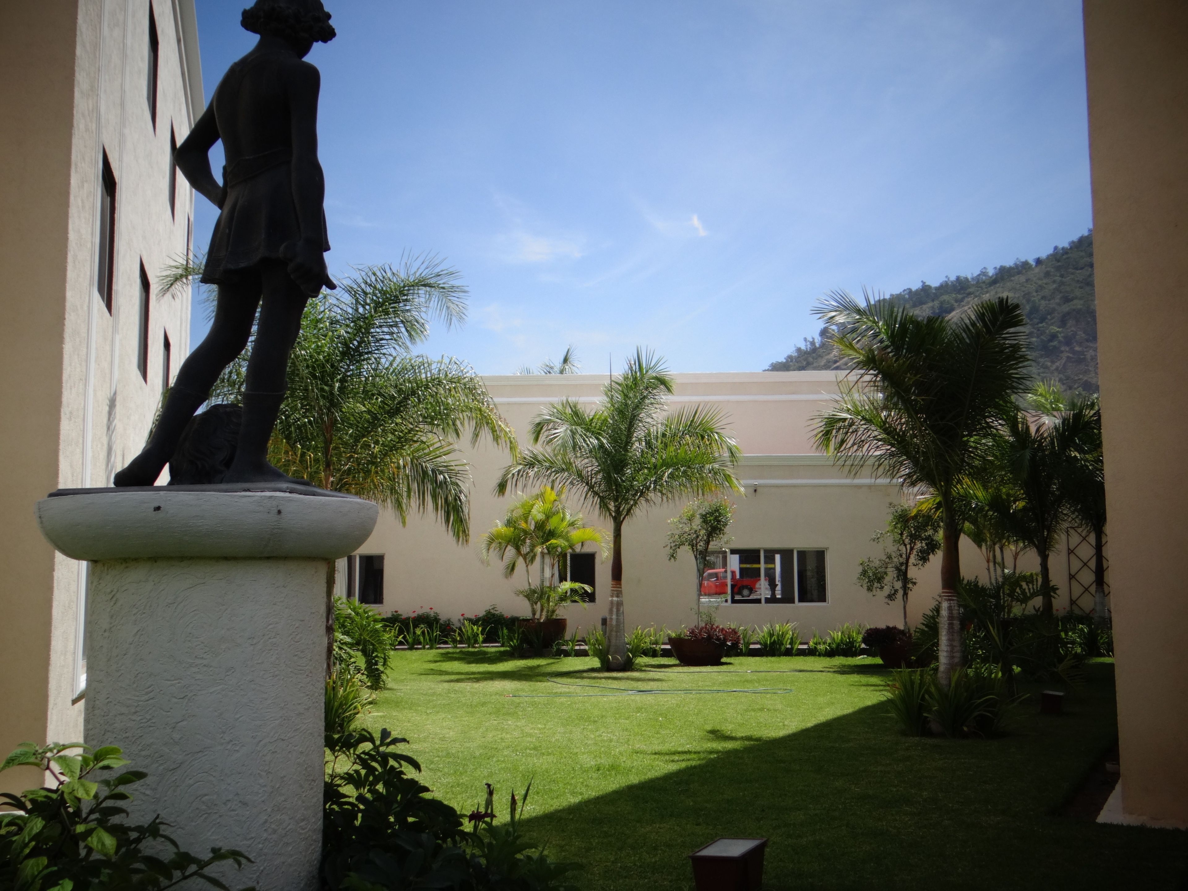 A statue in a courtyard with a building in the background.