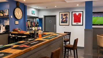 Eine Bar mit Uhr, gerahmten Sportmemorabilien und einem Fernsehbildschirm.