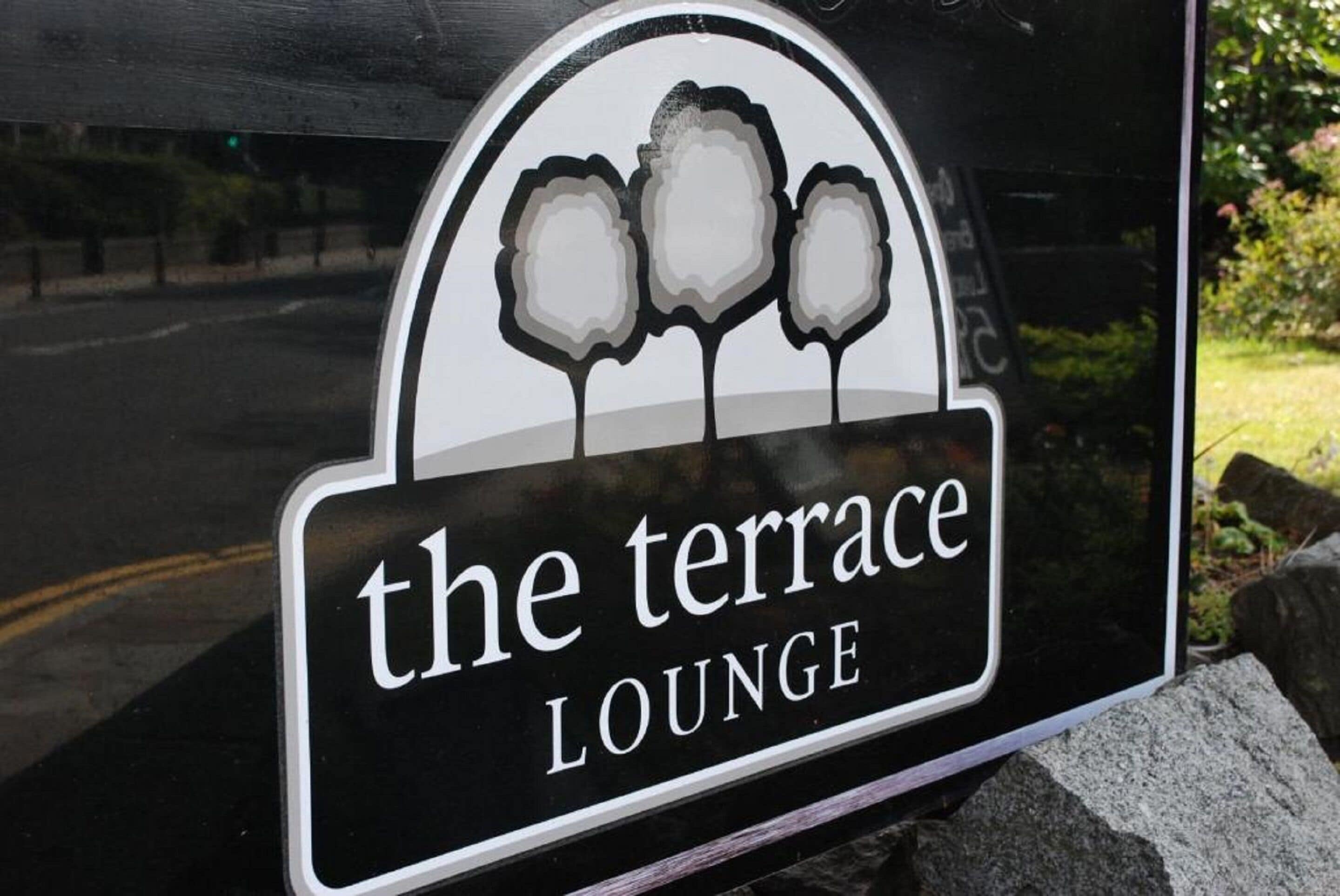 A sign for "The Terrace Lounge" with a logo featuring three stylized trees.