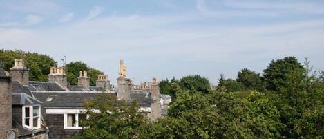 A residential area with stone houses, a prominent tower, and dense greenery.