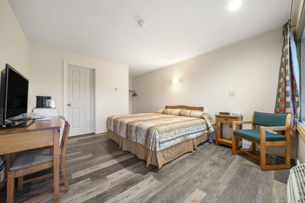 Une chambre à coucher avec un lit, un bureau, une chaise et un téléviseur.