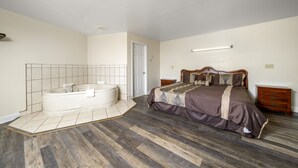 Ein Schlafzimmer mit einem großen Bett, einer separaten Badewanne und Holzboden.