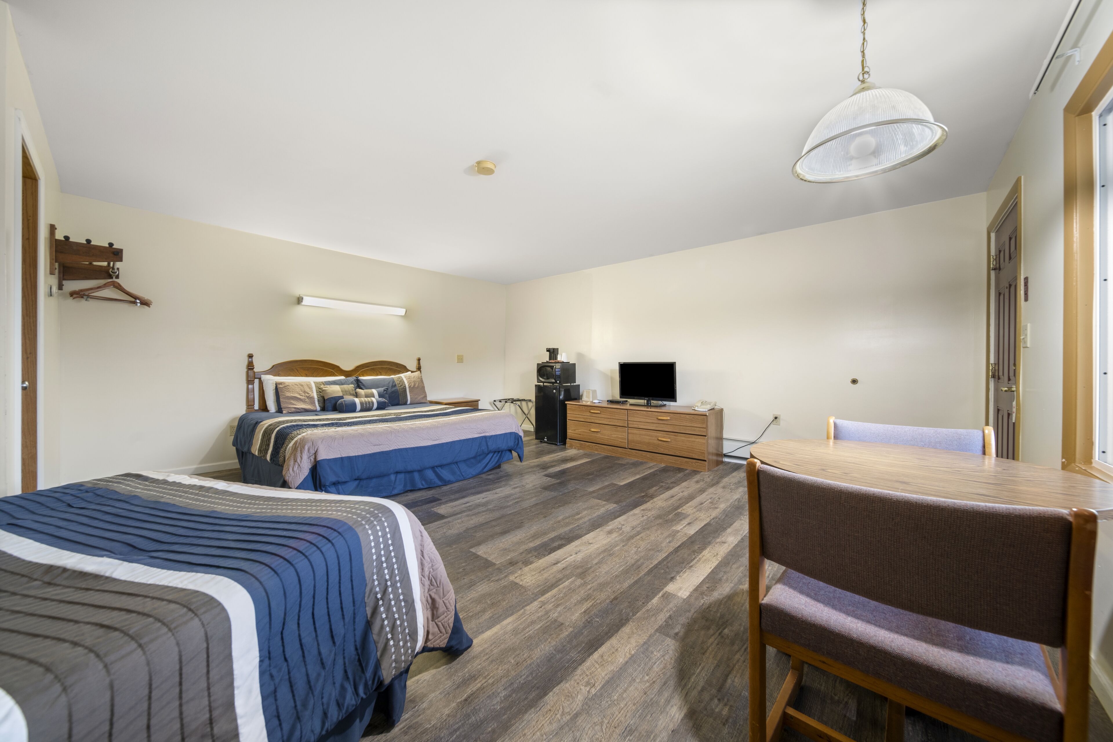 A bedroom with two beds, a desk, a chair, a TV, and a wardrobe.