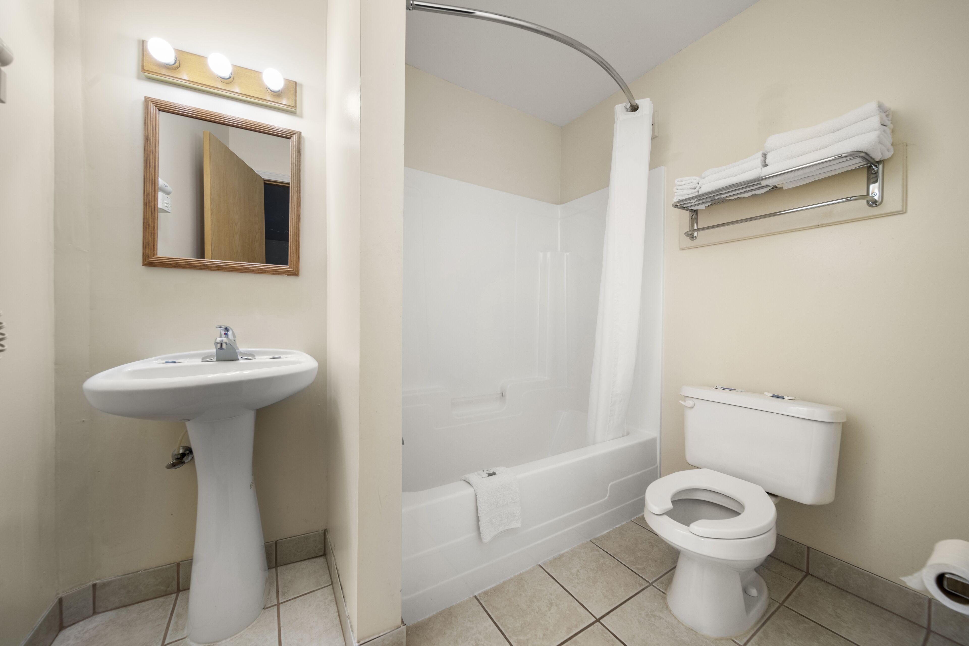 Un baño con lavamanos pedestal, bañera, inodoro y cortina de ducha.