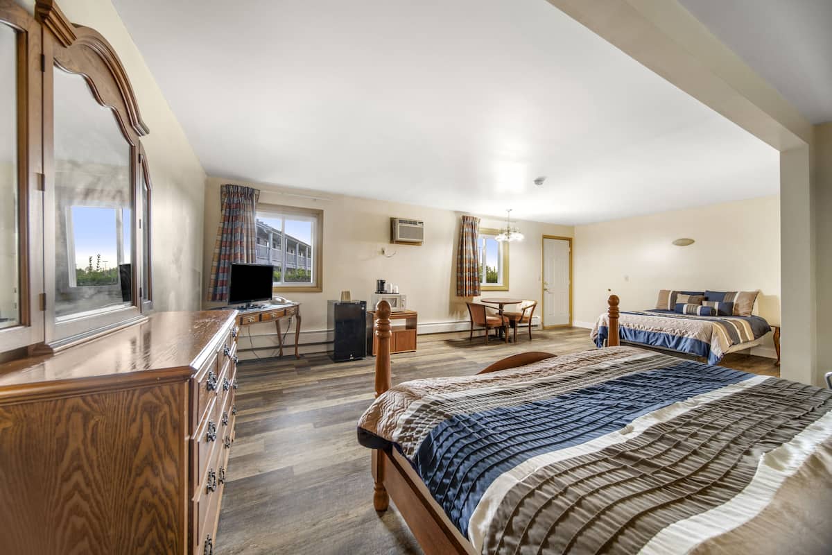 Une chambre d’hôtel avec deux lits, un bureau, une télévision et une vue sur l’extérieur.