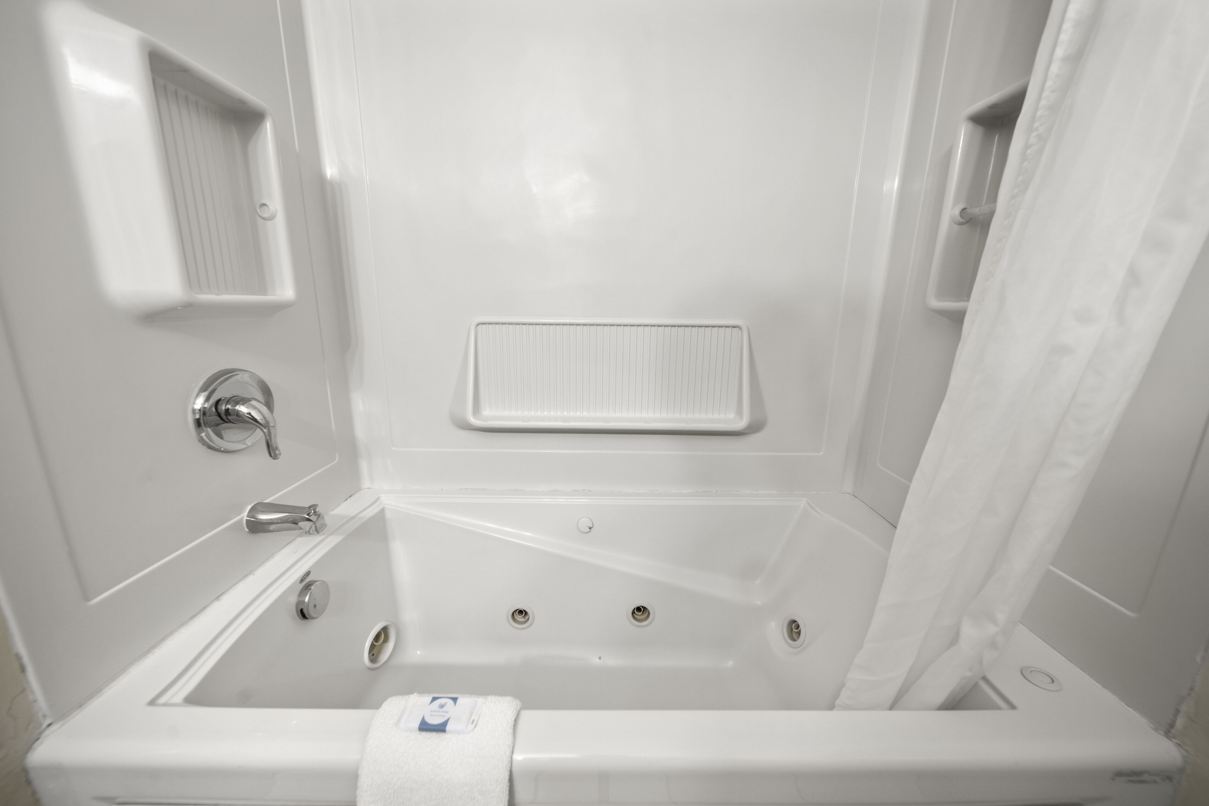 Un baño blanco con bañera, cortina de ducha y barra para toallas.