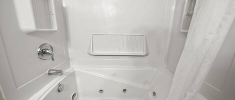 Un baño blanco con bañera, cortina de ducha y barra para toallas.