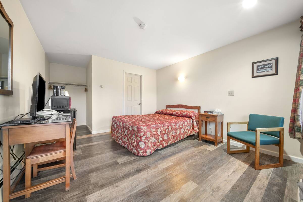 Une chambre à coucher comprenant un lit, un bureau, une chaise et un téléviseur.