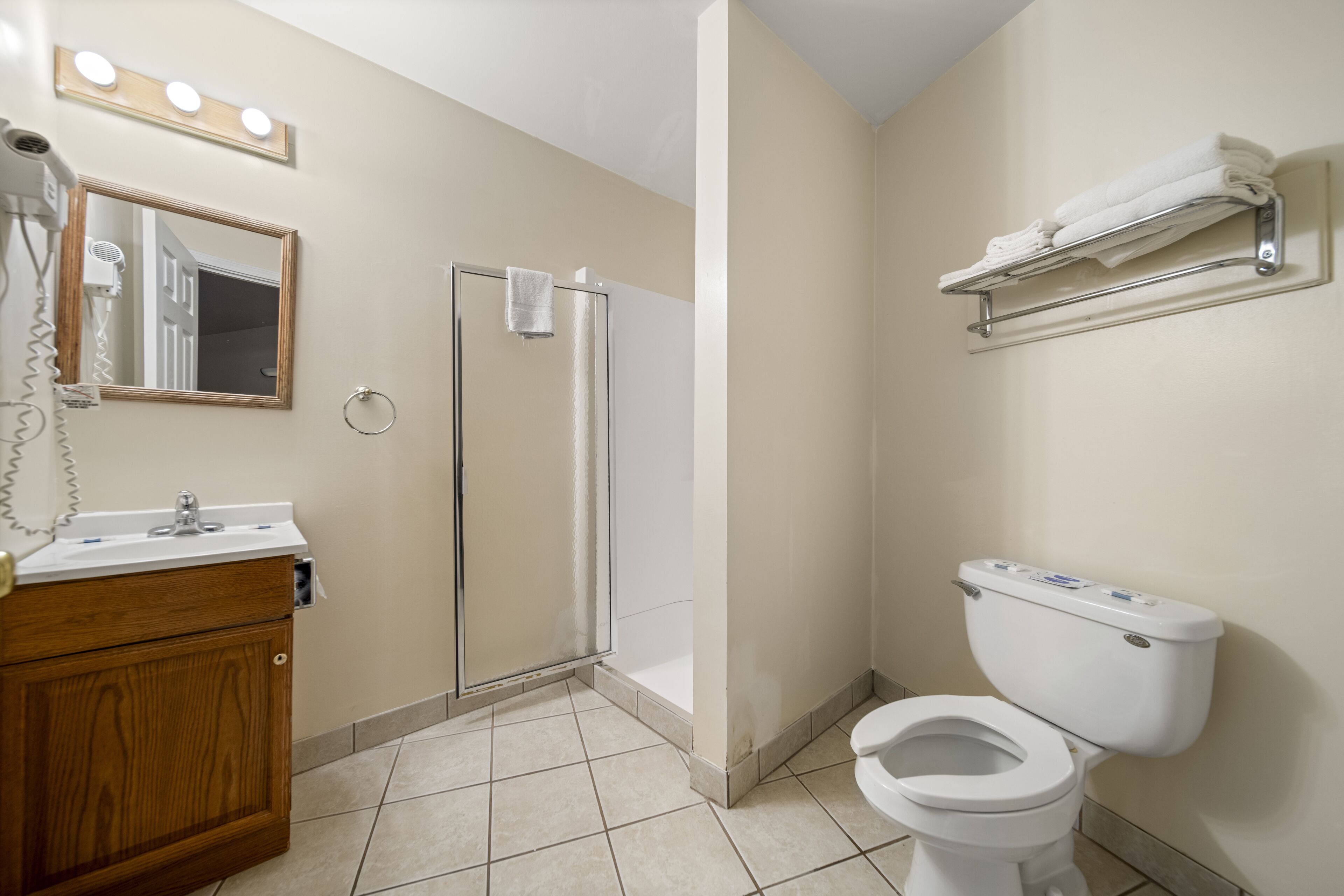 A bathroom with a vanity, a toilet, a shower, and a towel rack.