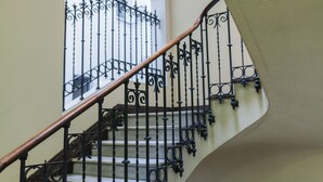 A staircase with ornate black metal railings and a wooden handrail. - Hostal Josefina (Madrid)
