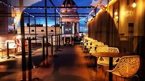 An outdoor seating area with tables and chairs, a decorative archway, and a building with a dome in the background. - Hostal Josefina (Madrid)