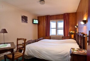 A hotel room with a bed, a desk with a chair, a television, and a window with curtains. - Hotel le Rouge Gazon (Saint-Maurice-sur-Moselle)