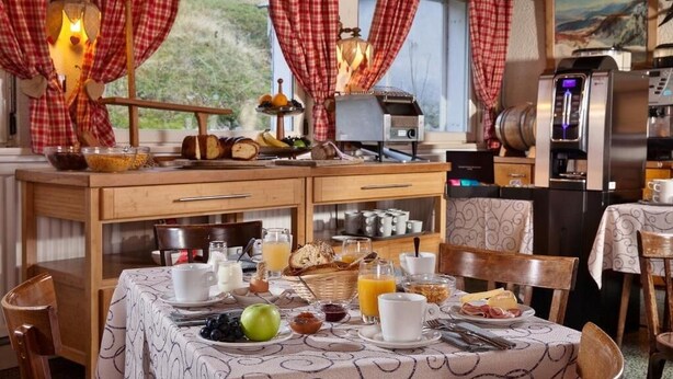 Un desayuno con una mesa para dos, que incluye pan, frutas y bebidas.