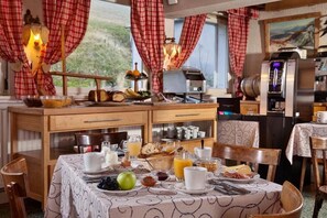 Un desayuno con una mesa para dos, que incluye pan, frutas y bebidas.