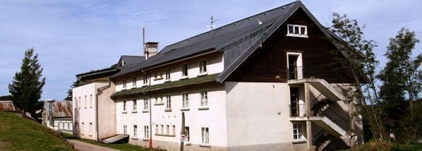 A large, multi-story building with a steeply pitched roof and a prominent staircase on the right side. - Hotel le Rouge Gazon (Saint-Maurice-sur-Moselle)