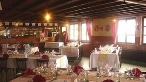 Un restaurante con mesas redondas dispuestas para comer, con manteles blancos y servilletas rojas.
