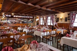 A restaurant with wooden interiors, multiple tables set for dining, and a bar area with various bottles. - Hotel le Rouge Gazon (Saint-Maurice-sur-Moselle)