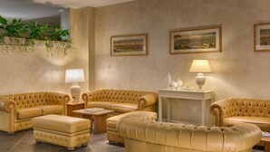 Un amplio salón con un sofá color beige, una mesa de centro y una mesita de noche con una lámpara.