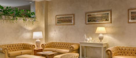 Un amplio salón con un sofá color beige, una mesa de centro y una mesita de noche con una lámpara.