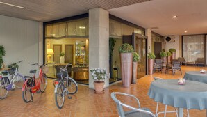Un espacio al aire libre moderno con mesas, sillas, un aparcamiento para bicicletas y plantas en macetas.