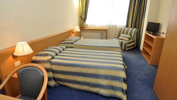 Camera d'albergo con due letti, una scrivania, una sedia, una TV e una finestra con tende.