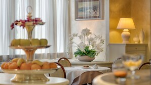 Un área de comedor con una mesa preparada para una comida, un arreglo floral y una lámpara en una mesita auxiliar.