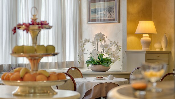 Un área de comedor con una mesa preparada para una comida, un arreglo floral y una lámpara en una mesita auxiliar.