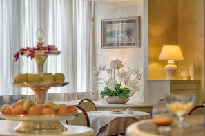 Un área de comedor con una mesa preparada para una comida, un arreglo floral y una lámpara en una mesita auxiliar.