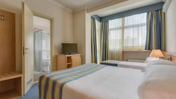 Ein Hotelzimmer mit einem Bett, einem Schreibtisch, einem Fernseher und einem durch eine offene Tür einsehbaren Badezimmer.