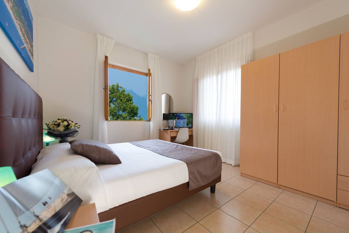 A bedroom with a bed, a desk, a TV, and a wardrobe.