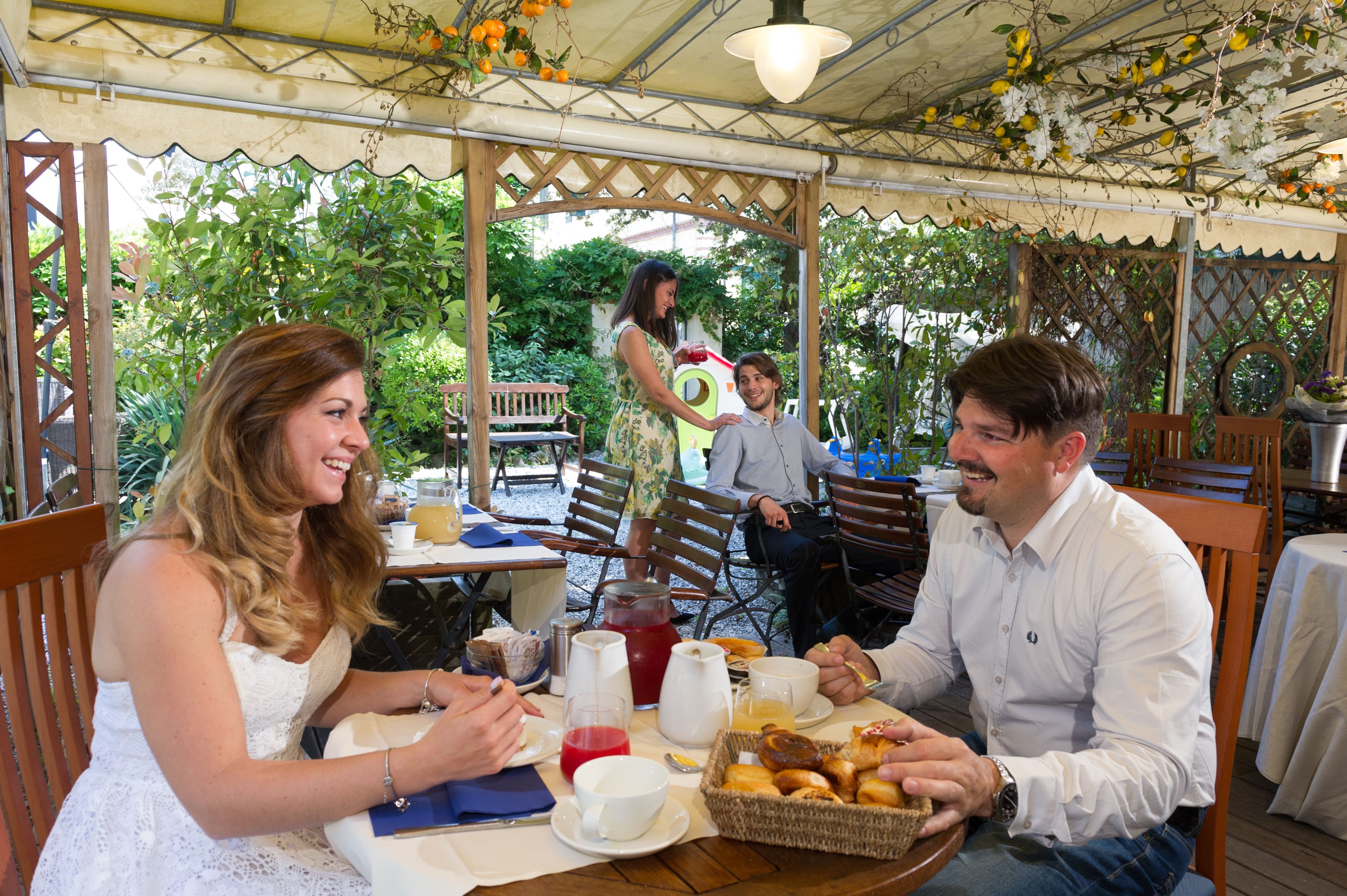 A covered outdoor dining area with tables, chairs, and a variety of food and drink items.